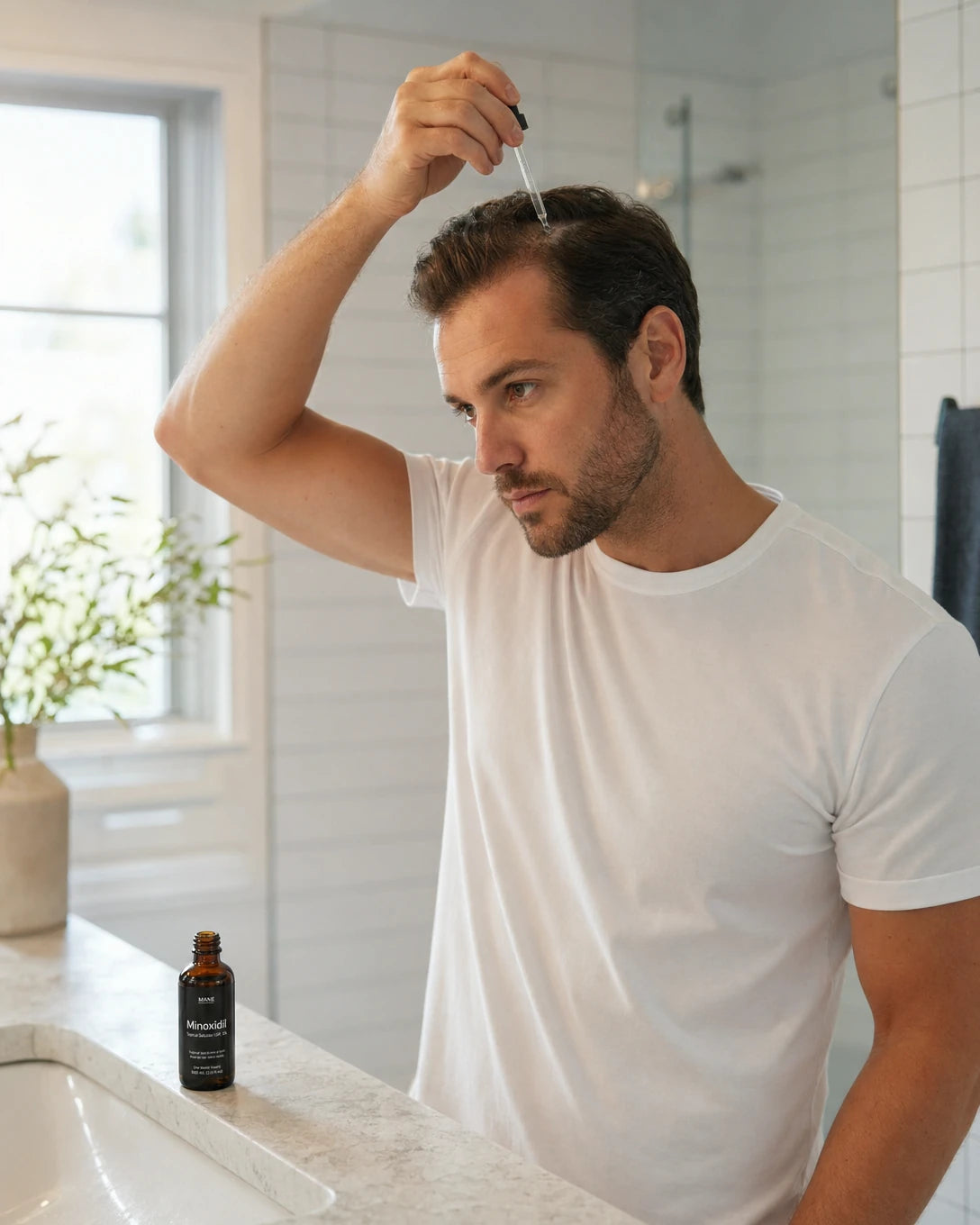 Man applying Minoxidil topical solution to scalp in bathroom — hair loss treatment men Australia